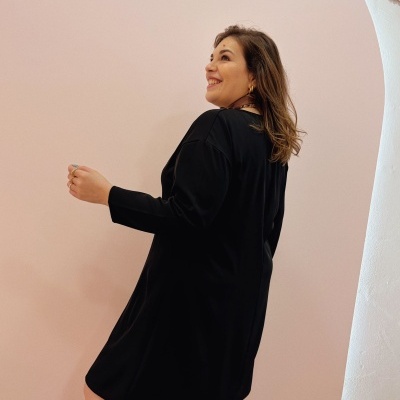 Mulher com vestido preto de manga comprida, fundo rosa