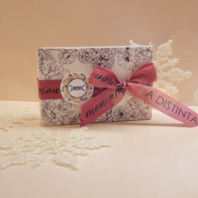 Caixa decorativa com padrão floral e fita rosa sobre superfície bege