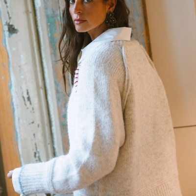 mulher com camisola de malha branca em ambiente interno com porta velha ao fundo