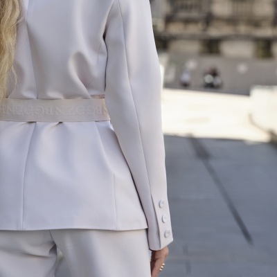 Blazer branco de senhora com cinto branco com texto em relevo visto da parte de trás