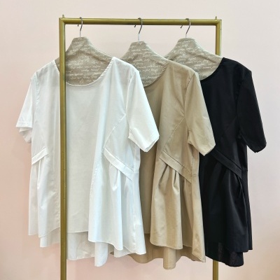 Vestidos branco, bege e preto pendurados em cabideiro metálico dourado com cabides forrados.