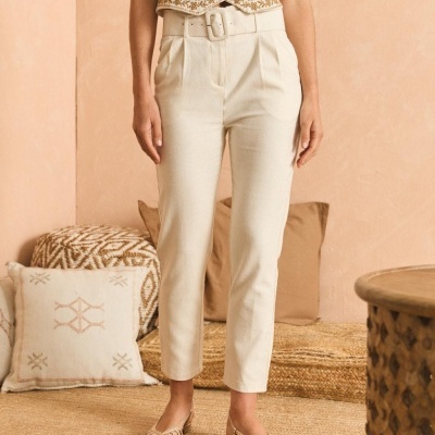 Calças bege claro com cinto largo, ambiente com almofadas decorativas bege e castanho