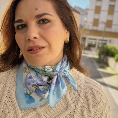 Cachecol de seda floral azul usado ao pescoço com camisola bege de malha