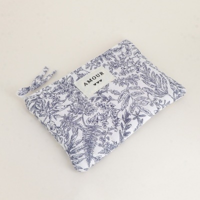 Mala de tecido branco com padrão floral azul e etiqueta AMOUR