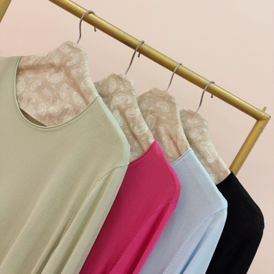 Quatro camisolas de manga comprida em cinco cores penduradas numa estrutura metálica dourada