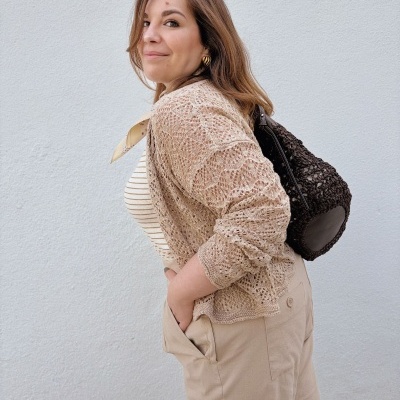 Mulher de cabelo castanho com roupa bege e mochila preta de malha
