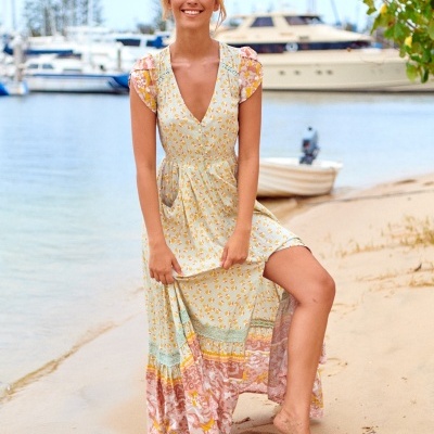 Vestido comprido com padrão floral colorido numa mulher numa praia