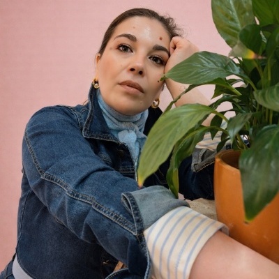 Mulher com casaco de ganga azul e planta em vaso castanho