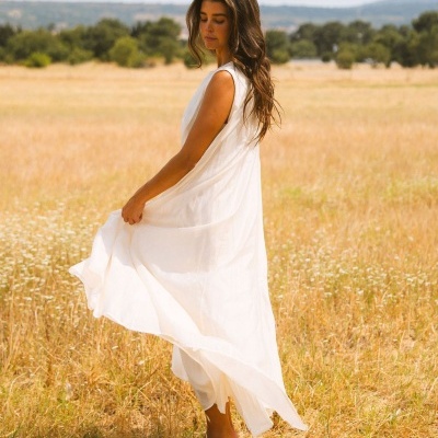 Mulher com vestido longo branco sem mangas em campo aberto
