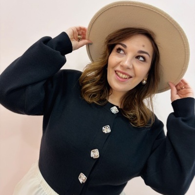 Mulher com chapéu bege e casaco preto com botões prateados