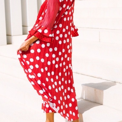 Vestido comprido vermelho com bolinhas brancas e folhos nas mangas.