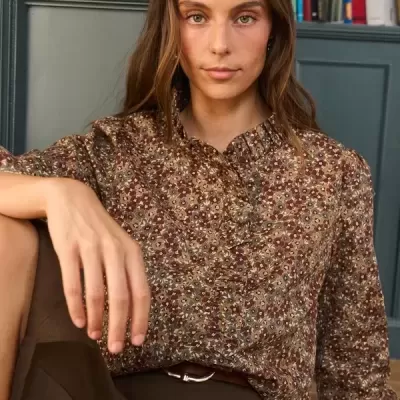 Camisa floral castanha com gola folhada e botões, calças castanhas e cinto castanho
