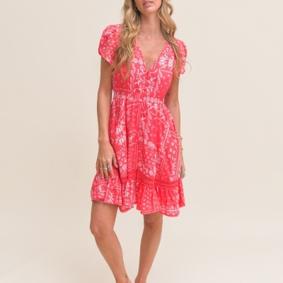 Vestido curto rosa com padrão branco floral e geométrico, decote em V e mangas curtas