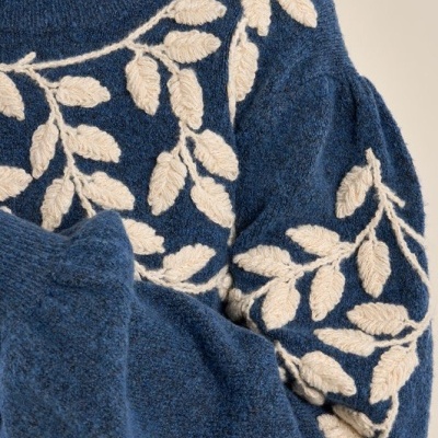 Suéter azul com padrão branco de folhas e mangas compridas