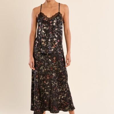 Modelo veste conjunto feminino preto com padrão floral e renda, sapatos pretos de salto alto.