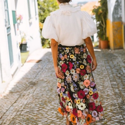 Saia midi preta com bordados florais coloridos e blusa branca de mangas bufantes