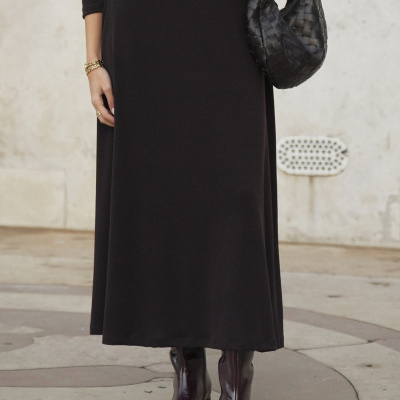 Vestido preto, bolsa trançada preta, botas castanhas e acessórios dourados