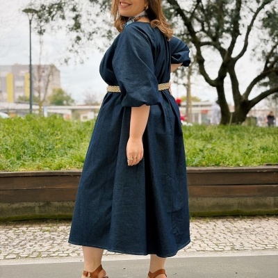 Mulher com vestido azul escuro, cinto bege e sandálias castanhas de salto grosso