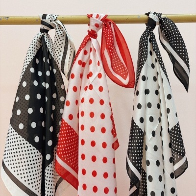 Três lenços de tecido com padrão de bolinhas pendurados numa barra dourada