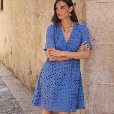 Vestido azul com perfurações usadas por mulher ao ar livre junto a parede