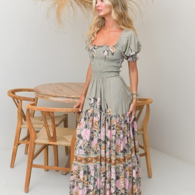 Vestido longo verde claro com flores rosas e castanhas, decote quadrado e mangas bufantes.