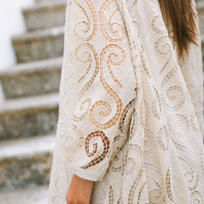 Manga em renda branca com padrão swirl e bordados em ambiente exterior com escadas de pedra.