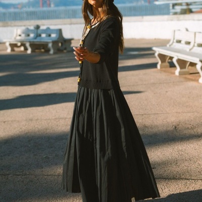 Mulher com vestuário preto e chapéu vermelho no exterior com bancos e ponte ao fundo