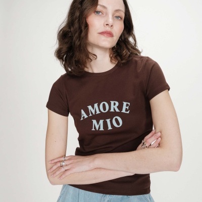 Mulher com t-shirt castanha com texto azul AMORE MIO e calça jeans azul clara