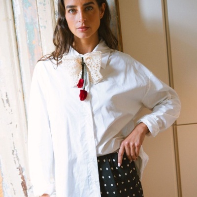 Camisa branca com laço de renda e rosas vermelhas, saia preta com bolinhas brancas