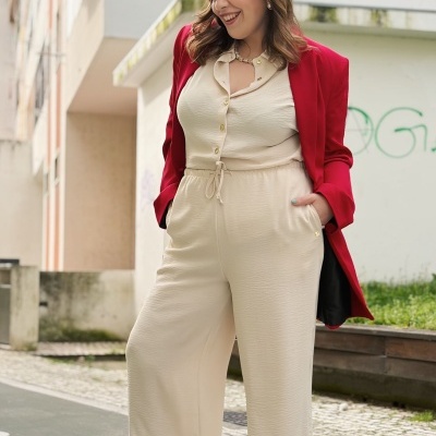 Mulher com conjunto creme e casaco vermelho em ambiente urbano