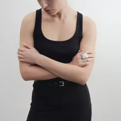 Mulher com top e calças pretas e anel prateado