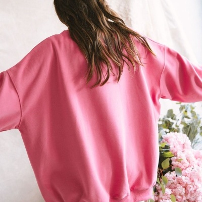 Sweatshirt oversized rosa vista de costas com flores ao fundo
