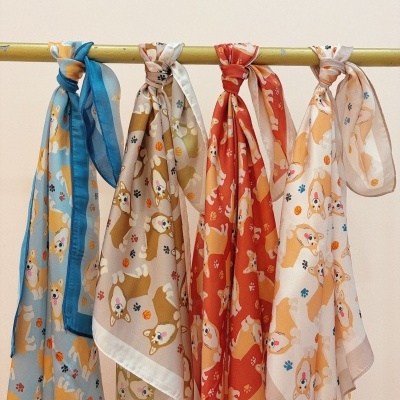 Quatro lenços coloridos com padrões de cães corgi pendurados num varão amarelo