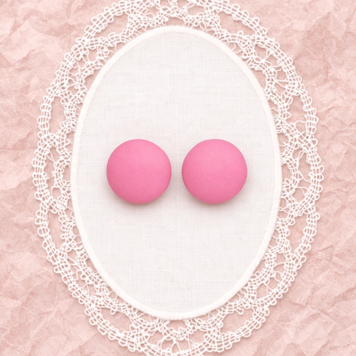 Dois macarrons cor de rosa em base rendada branca sobre fundo rosa enrugado