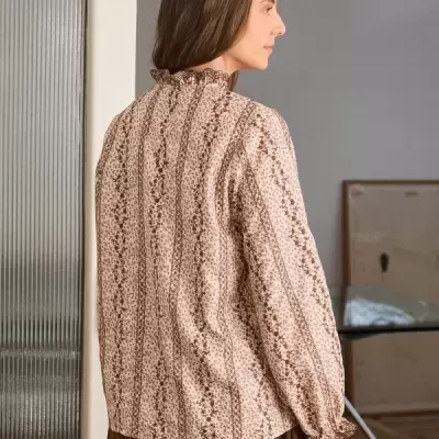 Blusa feminina bege com padrão floral castanho, vista de costas, com gola e punhos franzidos