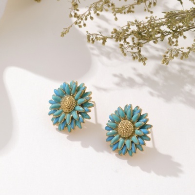 Brincos de flor azuis e dourados com fundo branco e flores secas