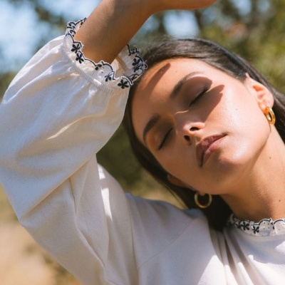 Blusa branca com renda preta e branca nos punhos em mulher ao sol