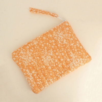 Necessaire laranja com padrão de flores pequenas brancas e fecho de correr
