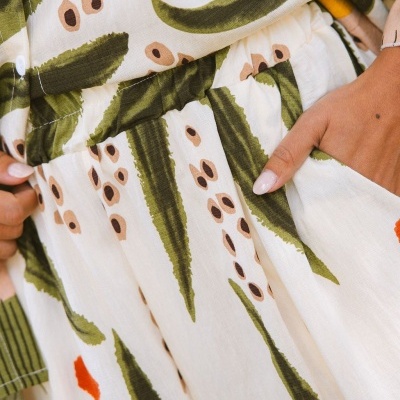 Vestido estampado com padrão verde, bege e laranja, detalhe de cintura elástica e bolso lateral.