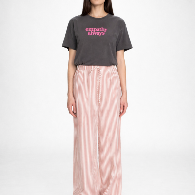 Mulher a vestir t-shirt cinzenta com texto rosa e calças largas riscas rosa e branco
