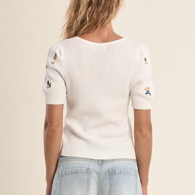 Camisola branca com bordados florais nas mangas e calças de ganga azul claro