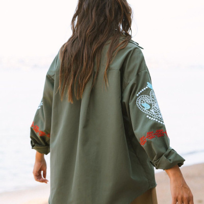 Camisa verde caqui com bordados nas mangas vista de costas na praia