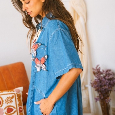 Camisa jeans azul com borboletas vermelhas no bolso vista de perfil