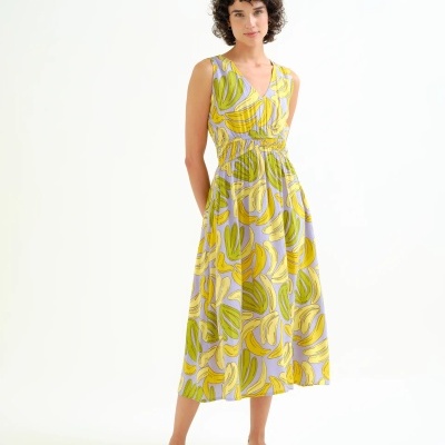 Vestido midi lilás com padrão de folhas amarelas e verdes, decote em V, usado com sandálias brancas