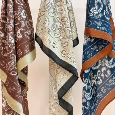Três lenços com padrão paisley em diferentes cores pendurados