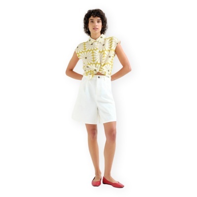 Mulher com camisa floral amarela e calções brancos