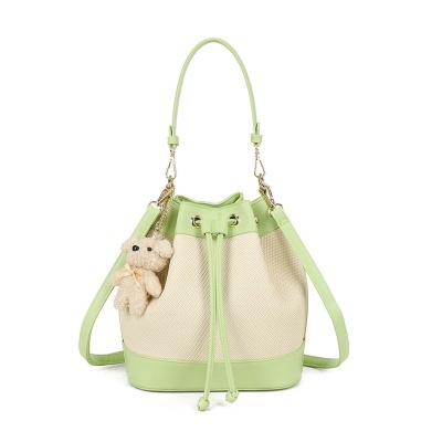 Saco de mão bege com acessórios verdes e ursinho de peluche pendurado