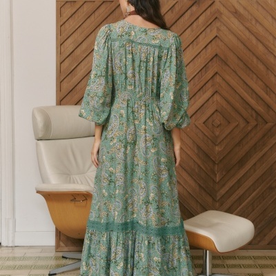 Vista traseira de vestido comprido feminino com padrão paisley verde, azul e bege, e mangas compridas com volume
