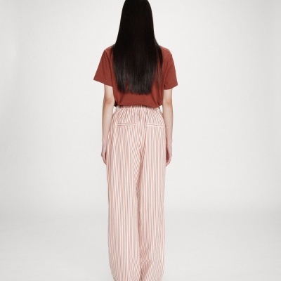 Calças largas com riscas brancas e vermelhas e t-shirt castanha vistas de costas
