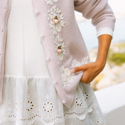 Cardigan rosa claro com botões decorativos florais e vestido branco bordado